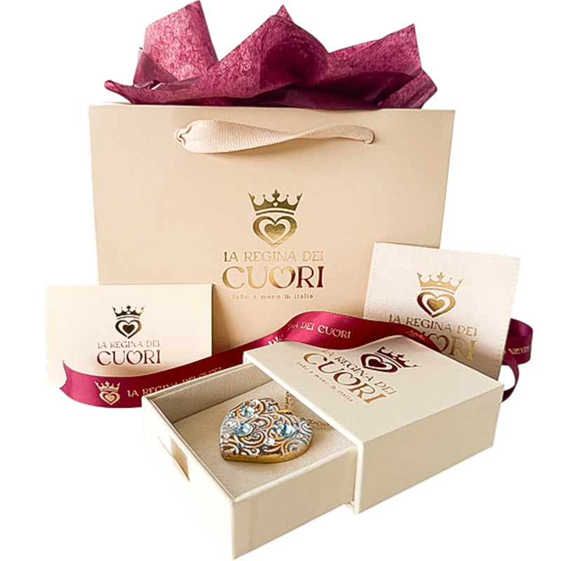 Dettaglio dell'elegante confezione regalo per gioielli a forma di cuore personalizzati. Collana personalizzata a cuore all'interno della sua esclusiva confezione regalo beige e bordeaux. Un gioiello artigianale illuminato da cristalli Swarovski, pronto per stupire con la sua dedica incisa sul retro.